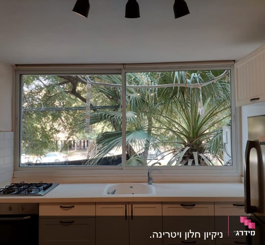 מטבח נקי עם חלון גדול ועץ בחוץ